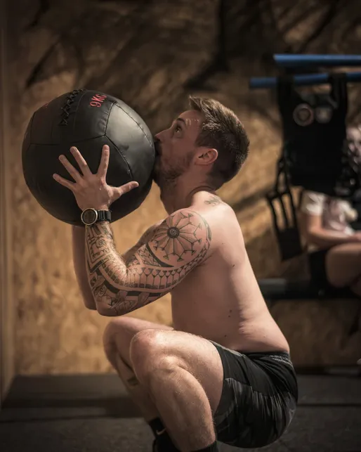 Séance de coaching sportif individuel chez Hornets Factory avec un sportif soulevant un medicine ball.
