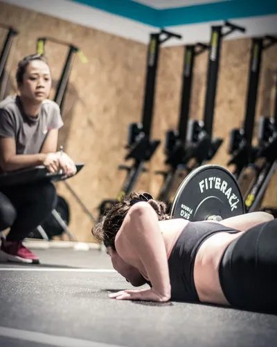 Une femme, concentrée, sur un ergonome rameur dans la salle de musculation de Hornets Factory - CrossFit Mazamet.
