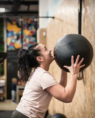 Une femme faisant un Kettle Bell Swing, devant une rangée d'ergonomes.