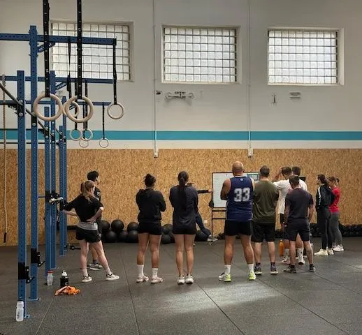 Groupe concentré en séance de functional fitness chez Hornets Factory et coach Elodie qui explique les exercices du WOD.