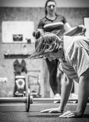 Une femme effectue un burpee lors d'une séance de préparation Hyrox.