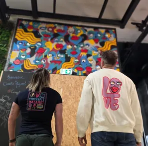 Un homme et une femme, de dos, regardant une fresque murale à l'intérieur de la box CrossFit Mazamet.