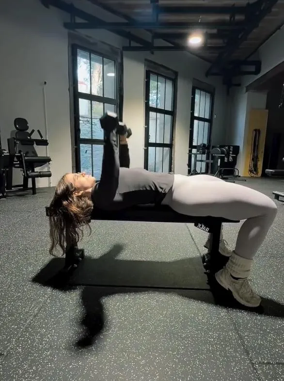 Femme effectuant un développé couché avec des haltères dans la salle de musculation CrossFit Mazamet