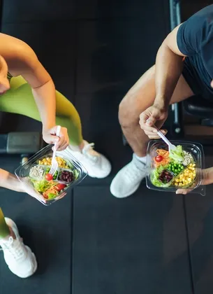 Un homme torse nu portant des barquettes de nourriture saine dans ses mains